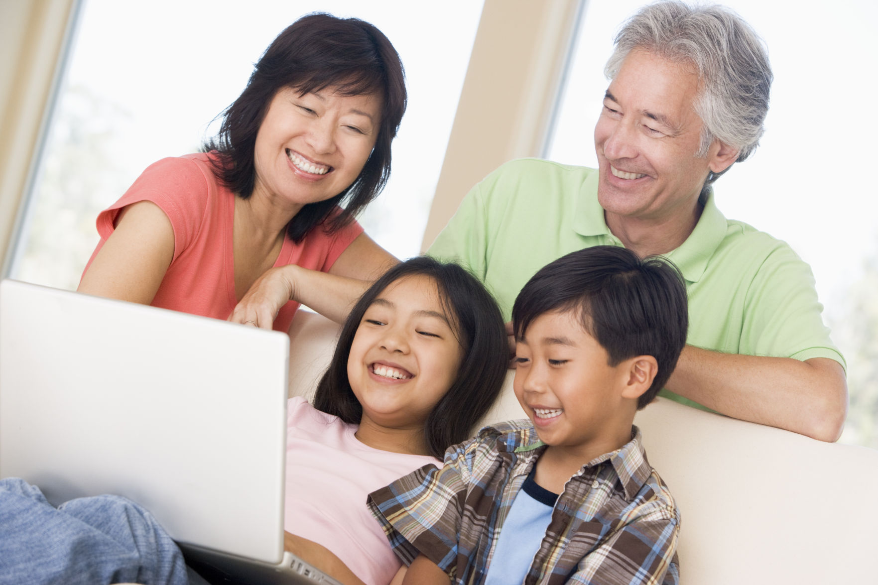 Couple with two young children in living room with laptop smiling